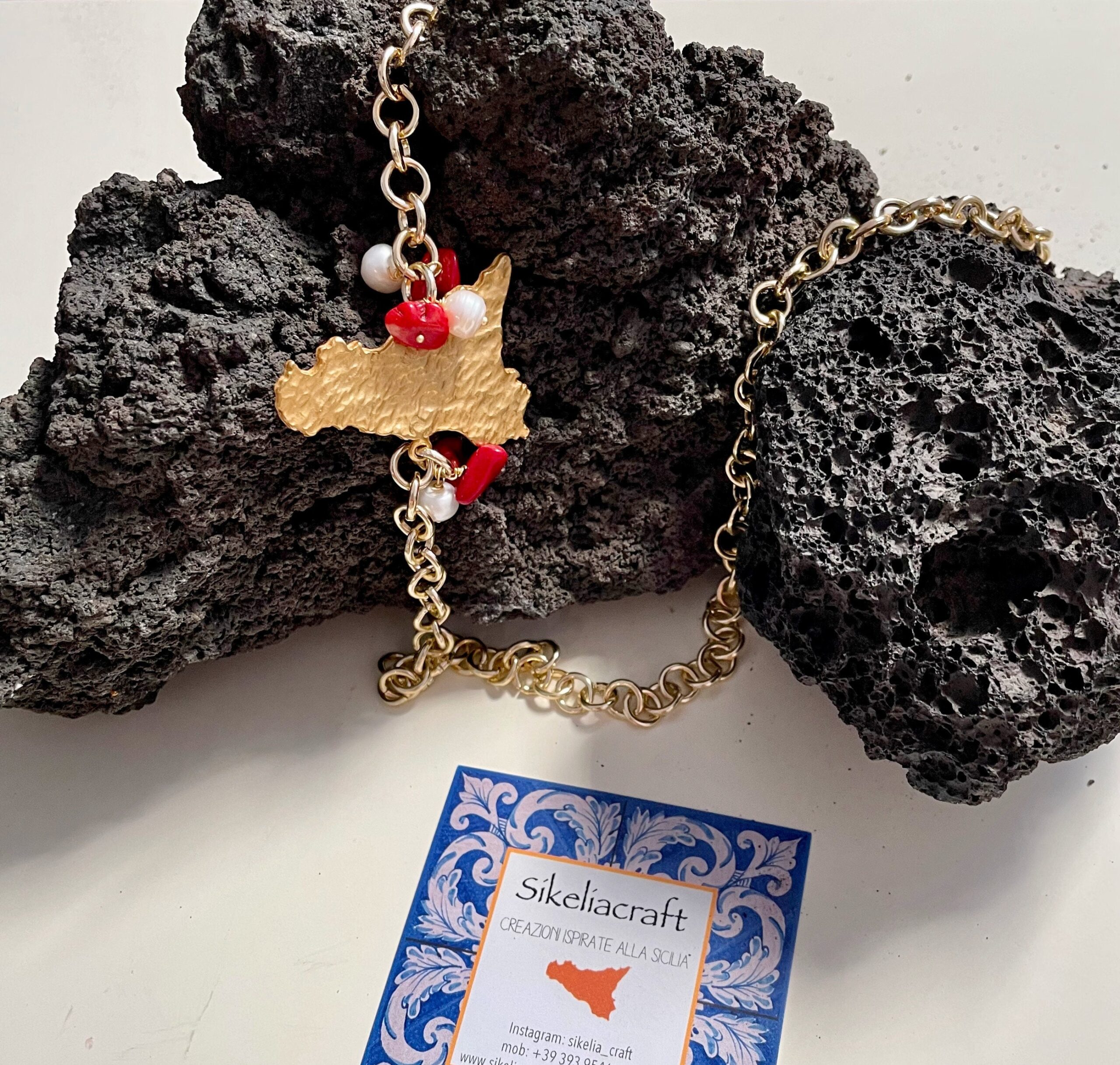 Collana con ciondolo sicilia in ottone, catena alluminio, perle di fiume e chips di corallo. Collane caratteristiche siciliane