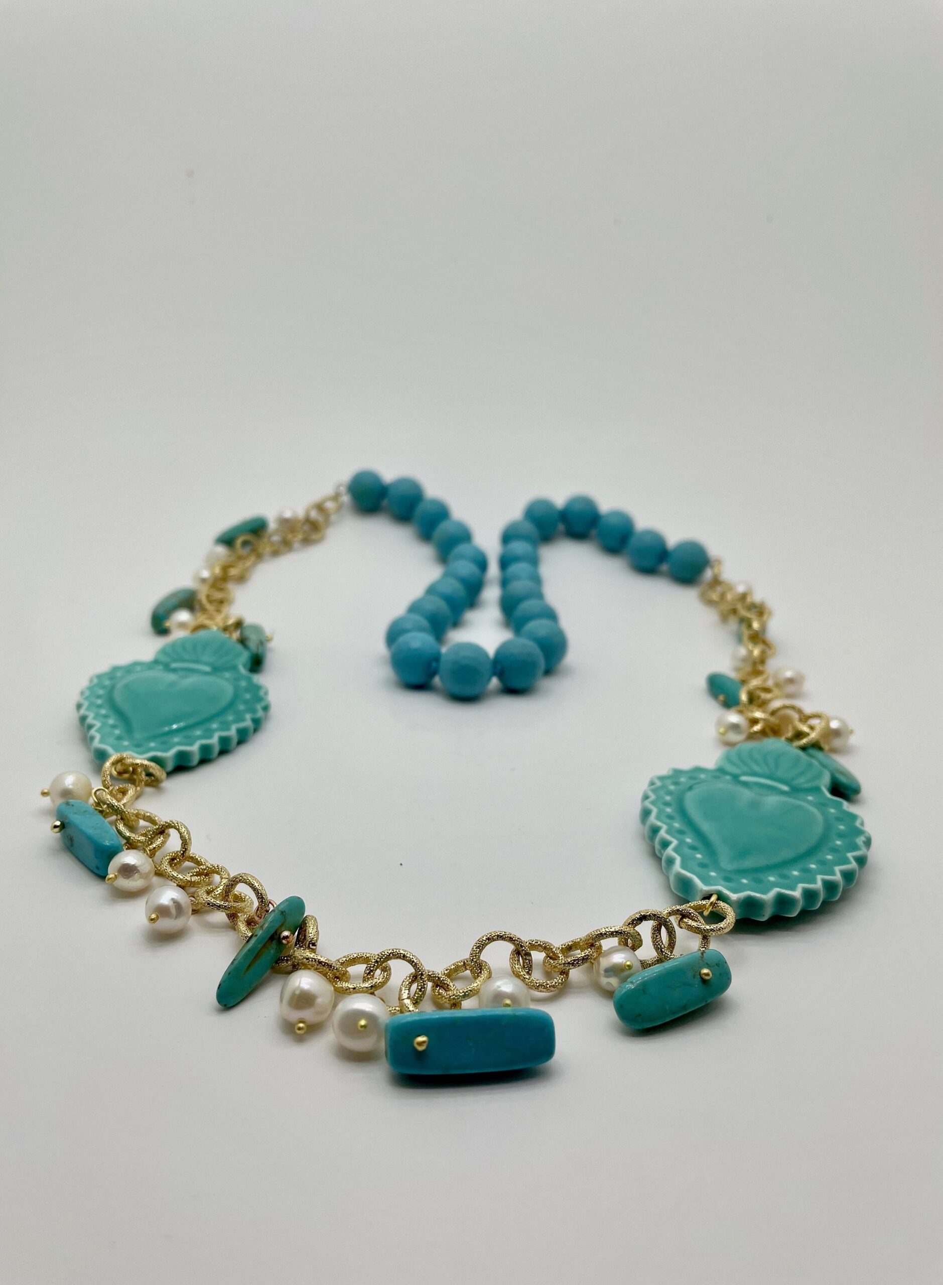 Collana lunga turchese, cuori sacri in ceramica di Caltagirone, perle di fiume, pasta di turchese, chips turchesi, catena alluminio dorata. Collane caratteristiche siciliane
