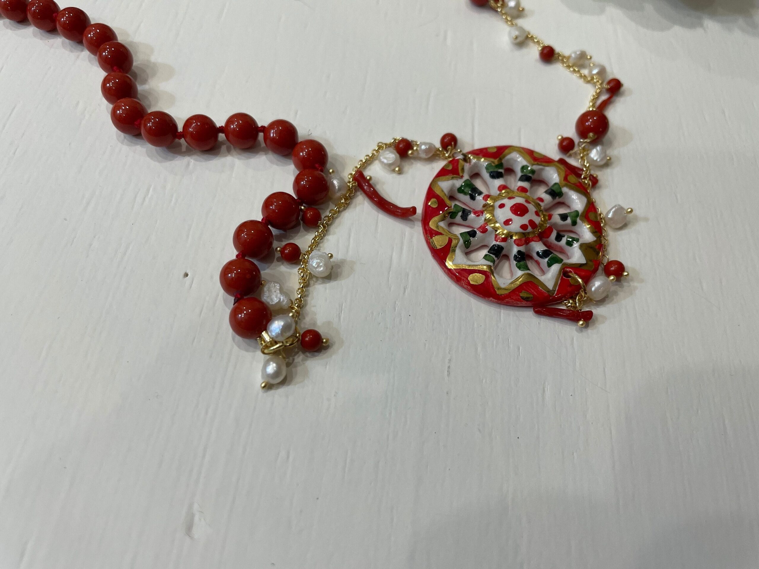 Collana siciliana con ruota di carretto in ceramica di Caltagirone, perle maiorca rosse e corallo. regalo per lei. Collane caratteristiche siciliane